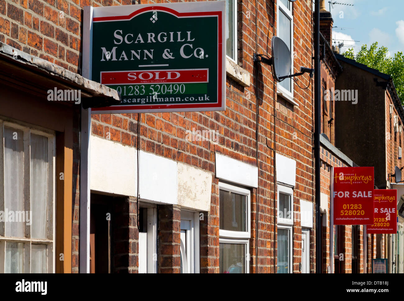 For Sale and Sold signs outside traditional red brick terraced houses in Tutbury Staffordshire England UK Stock Photo