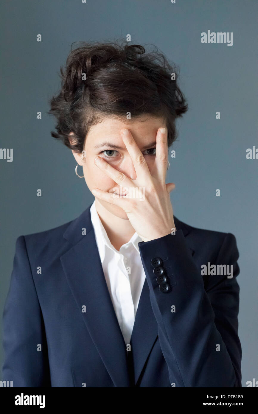 Mid adult woman covering her eyes in embarrassment Stock Photo