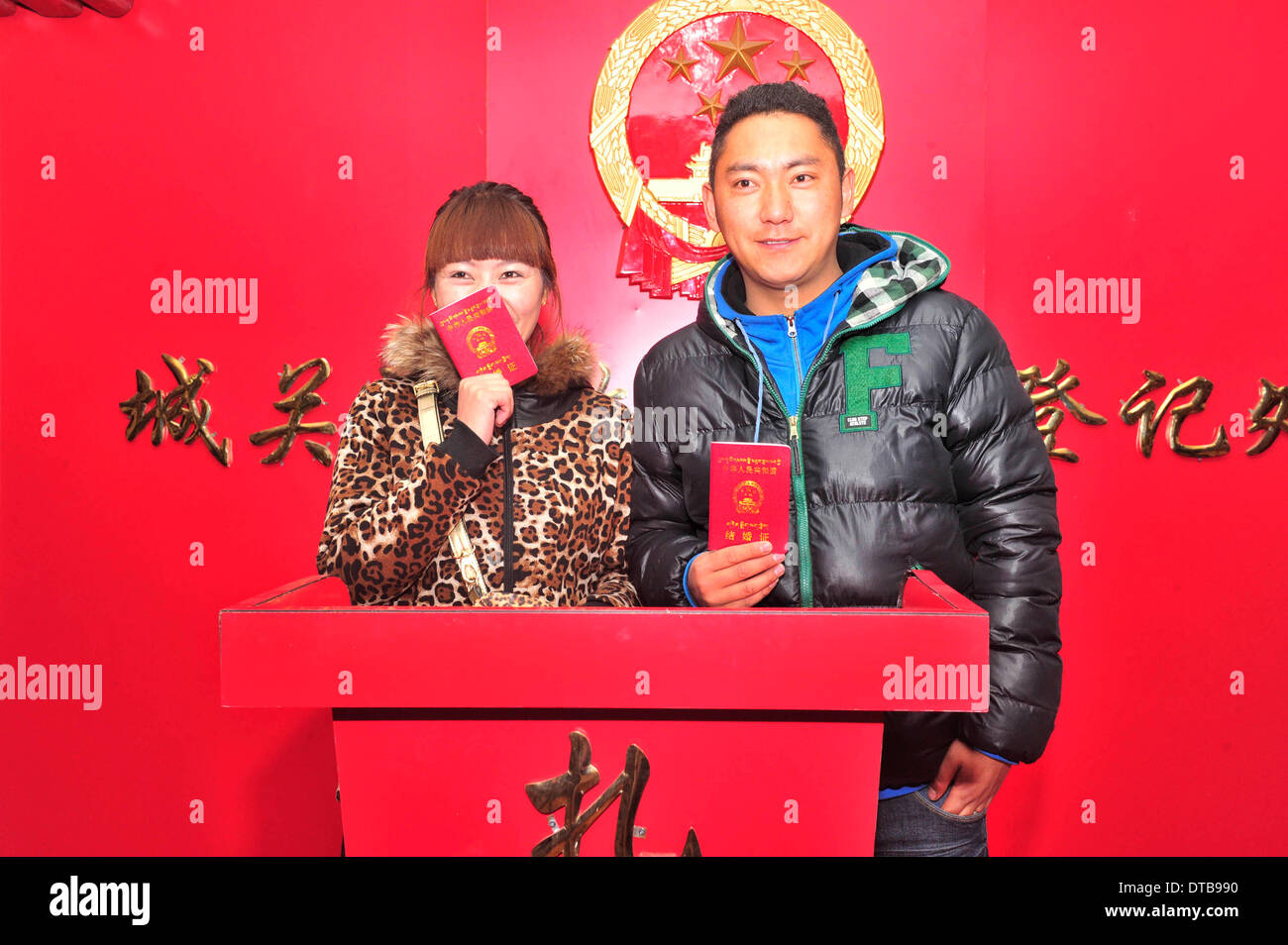 Lhasa, China's Tibet Autonomous Region. 14th Feb, 2014. Newlyweds holding their marriage certificates pose for photos at a marriage registry on the Valentine's Day as well as the Chinese traditional Lantern Festival in Lhasa, capital of southwest China's Tibet Autonomous Region, Feb. 14, 2014. Many newlyweds chose to get marriage licenses on the Valentine's Day this year, as it coincides with the Lantern Festival, the 15th day of the first month of the Chinese lunar calendar. © Liu Kun/Xinhua/Alamy Live News Stock Photo