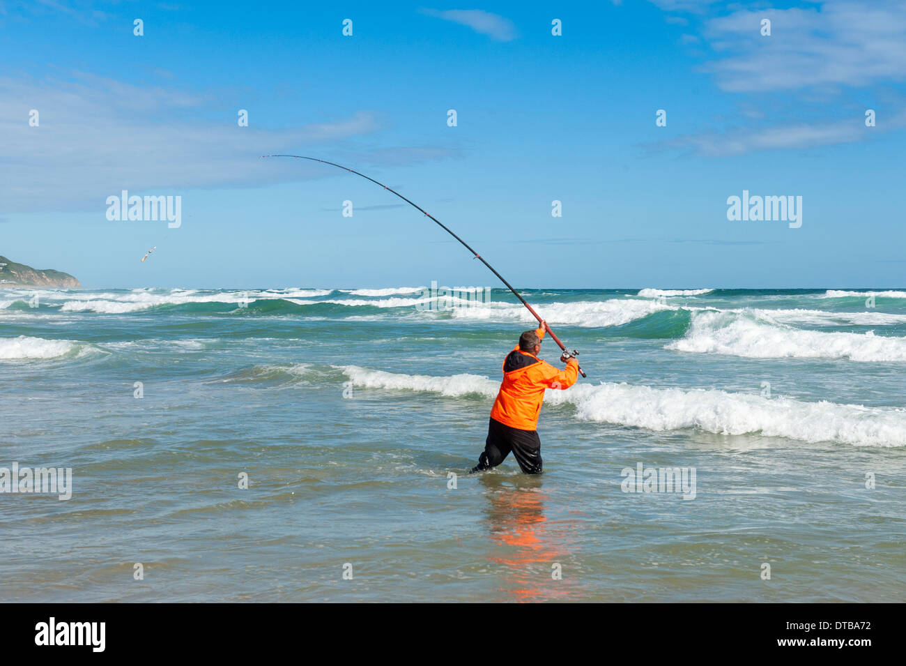 Fisherman casting a fishing rod standing in breaking waves, Sedgefield, Eastern Cape, South Africa Stock Photo