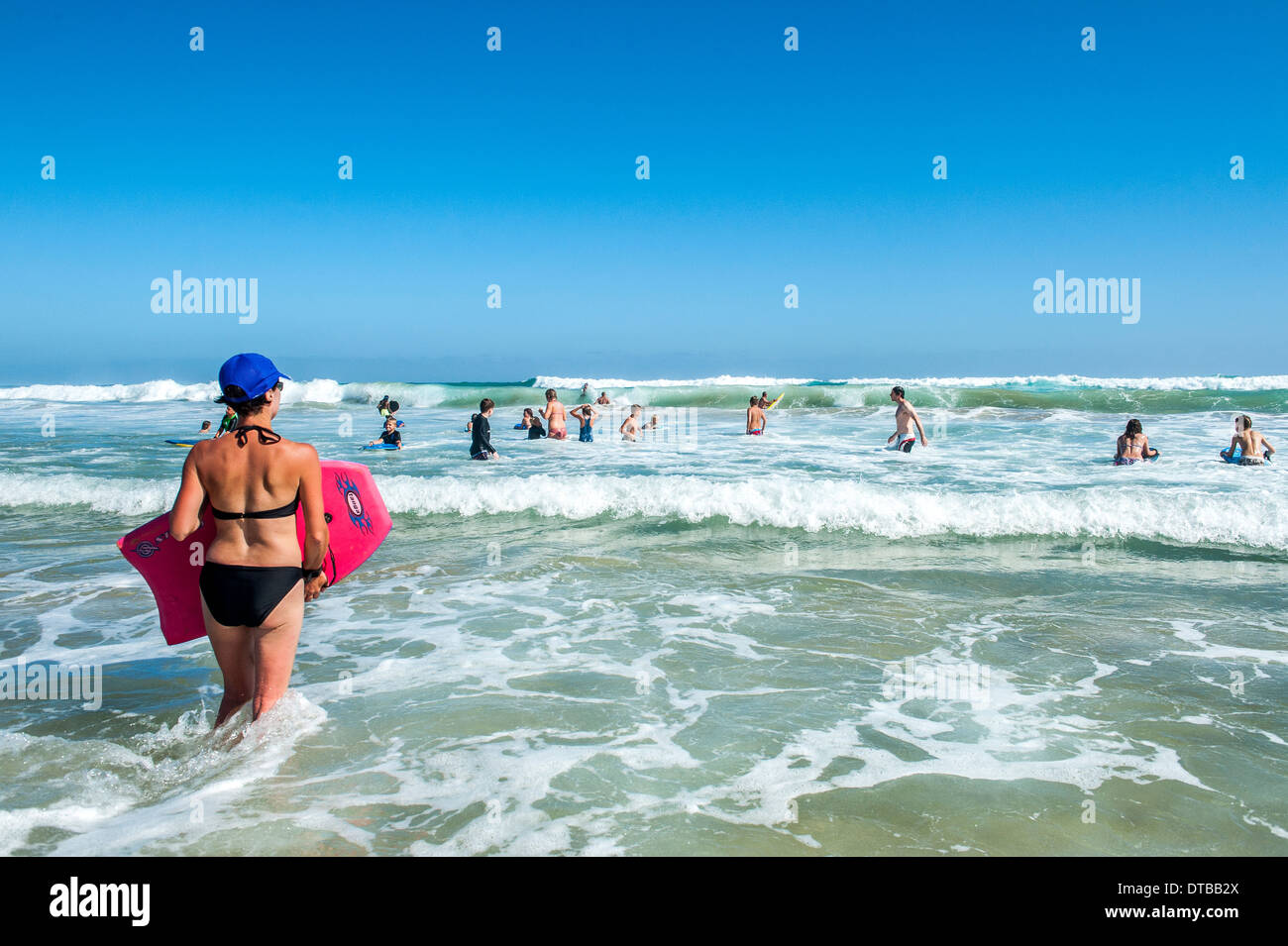 Woman carrying body board walking into the sea, Sedgefield, Eastern Cape, South Africa Stock Photo