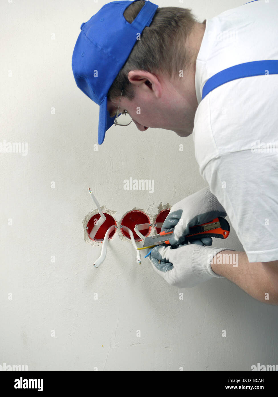 Electrician stripping electrical wires for wall socket Stock Photo