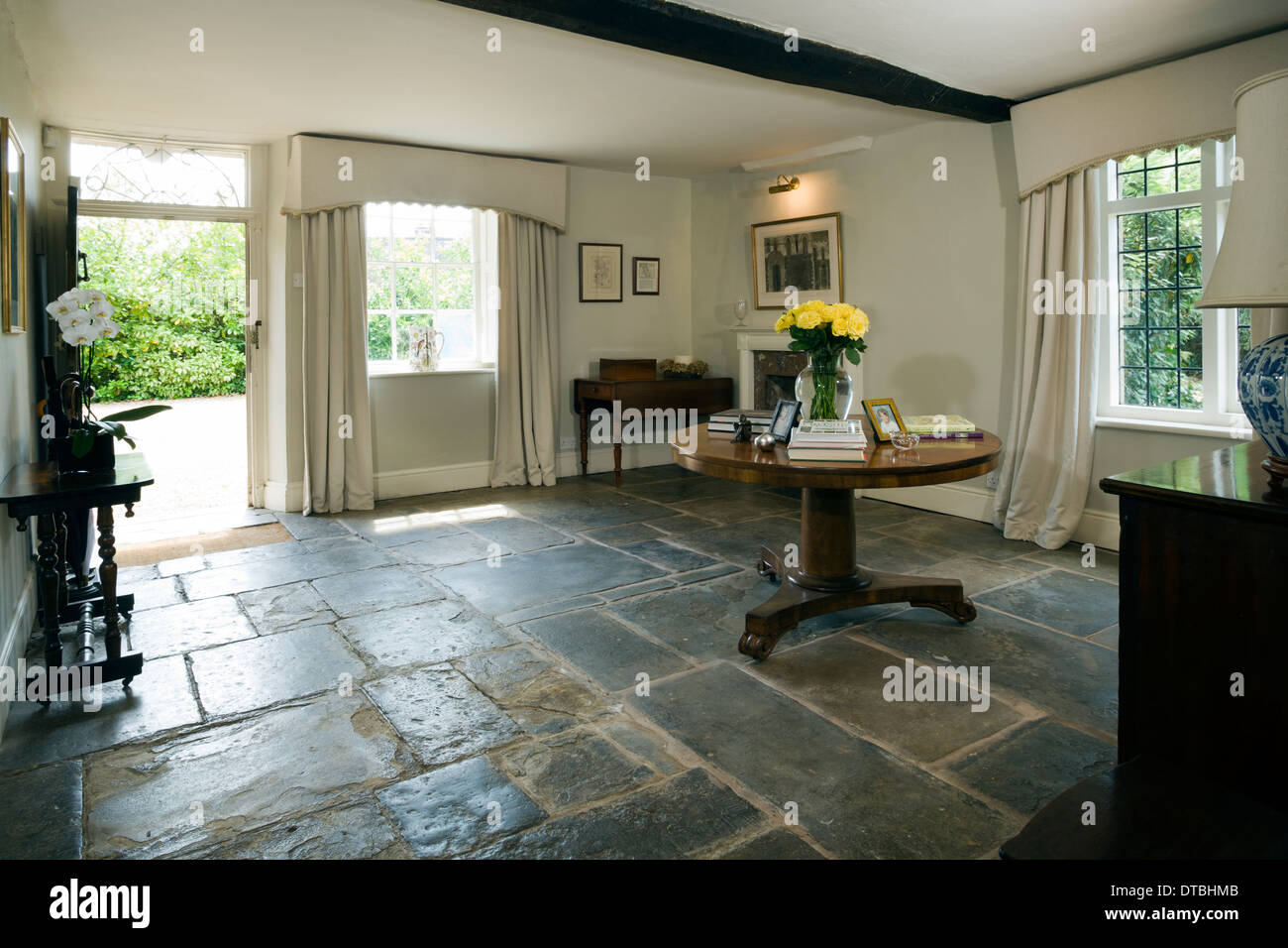 Large traditional entrance hall with stone flag floor. Front door Stock