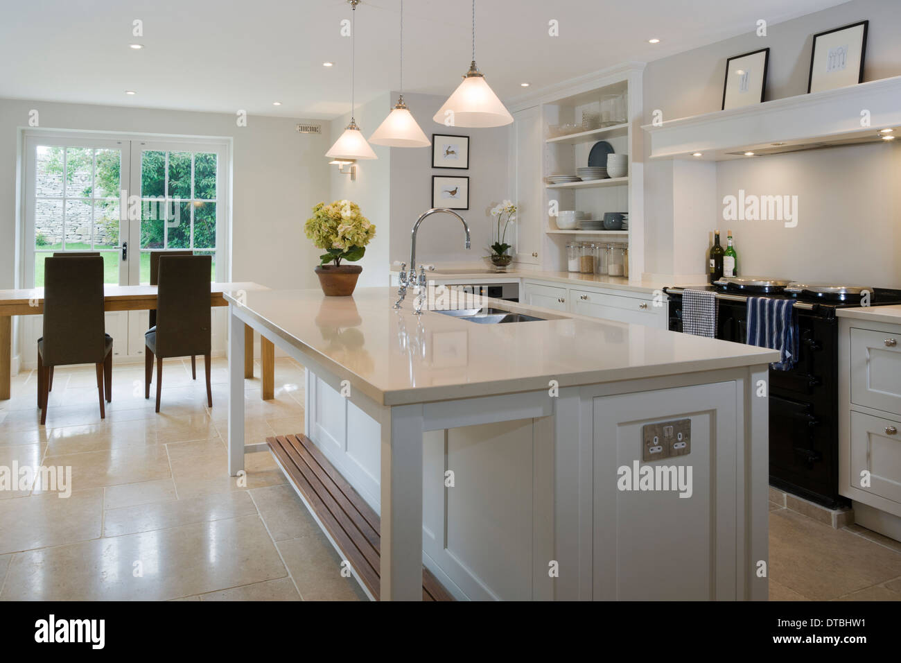 Large island unit in a bright light kitchen with dining area beyond. Stock Photo