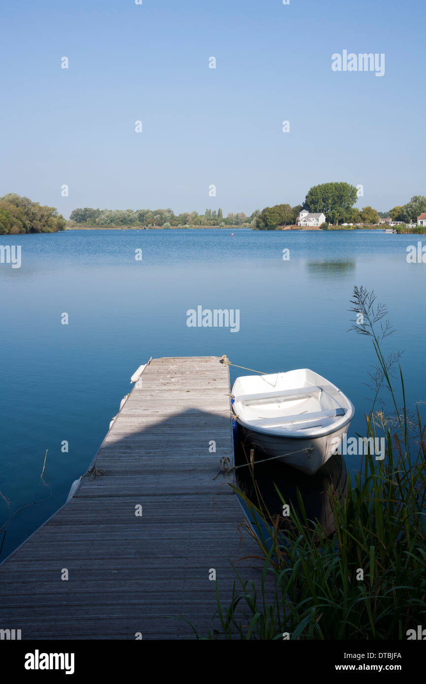 A small boat moored on a lake at the Cotswold Water Park holiday home complex, Gloucestershire, England, UK Stock Photo