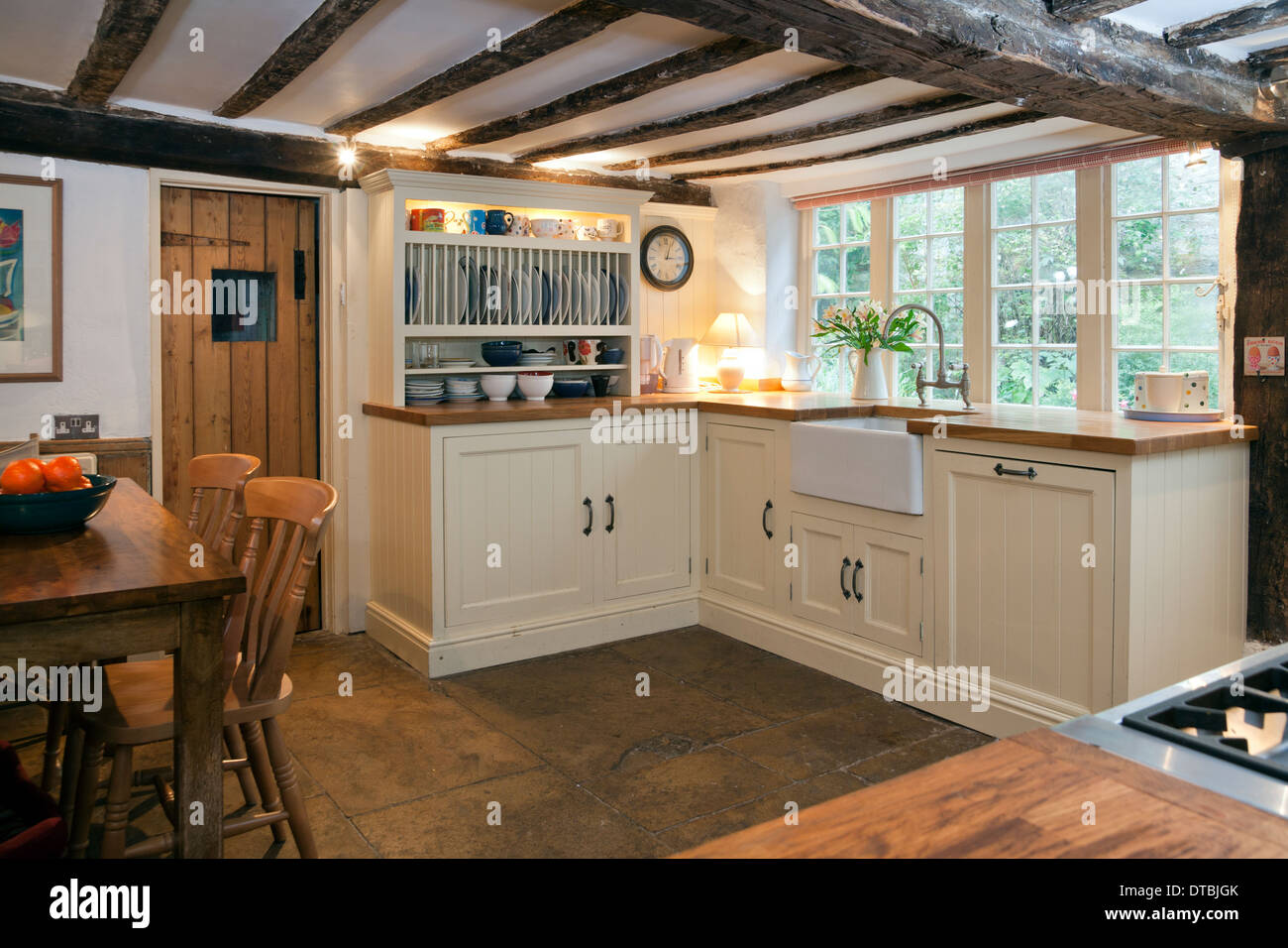 Period beamed ceiling small kitchen with paint finished fitted units and butler sink Stock Photo