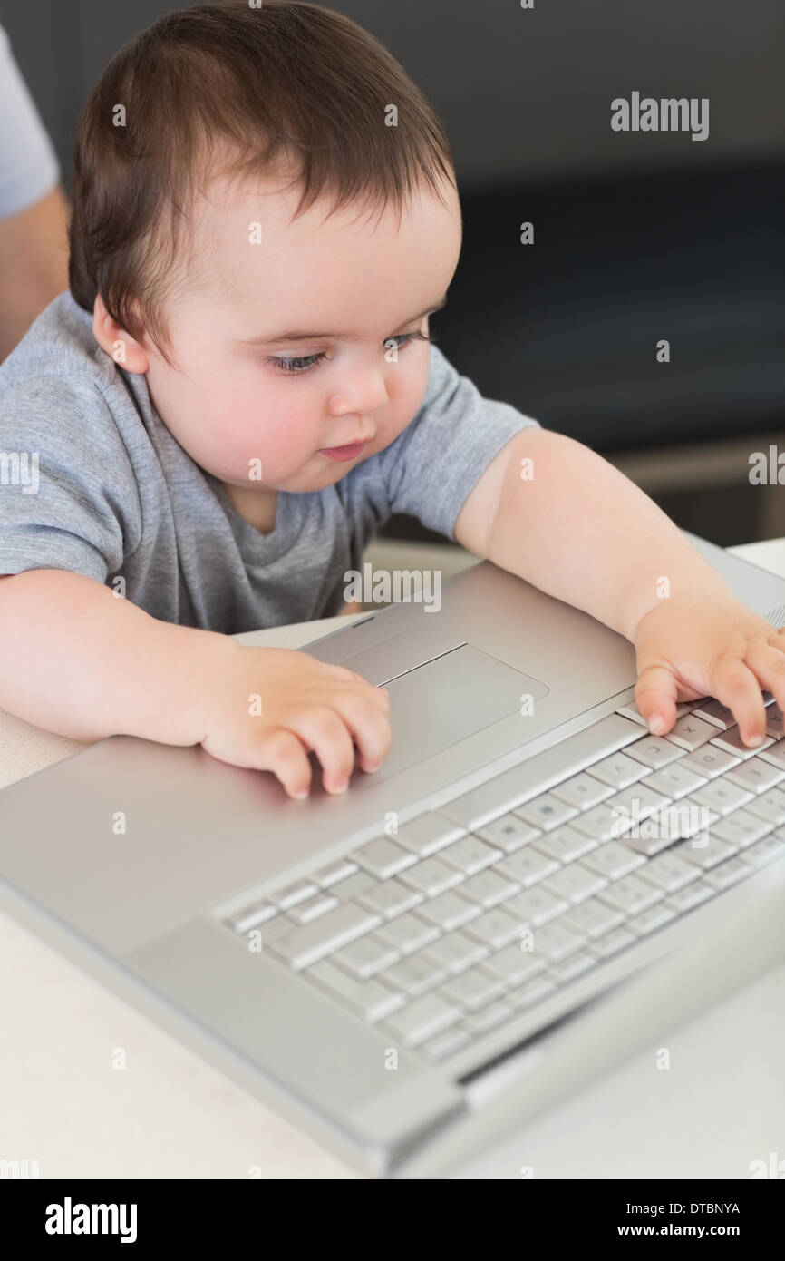 Baby using laptop at table Stock Photo