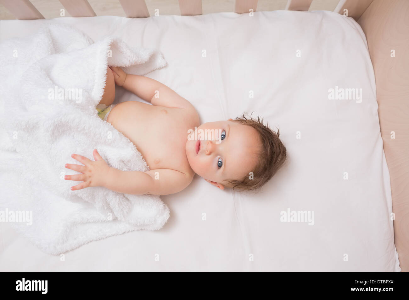 Adorable baby boy lying in crib Stock Photo