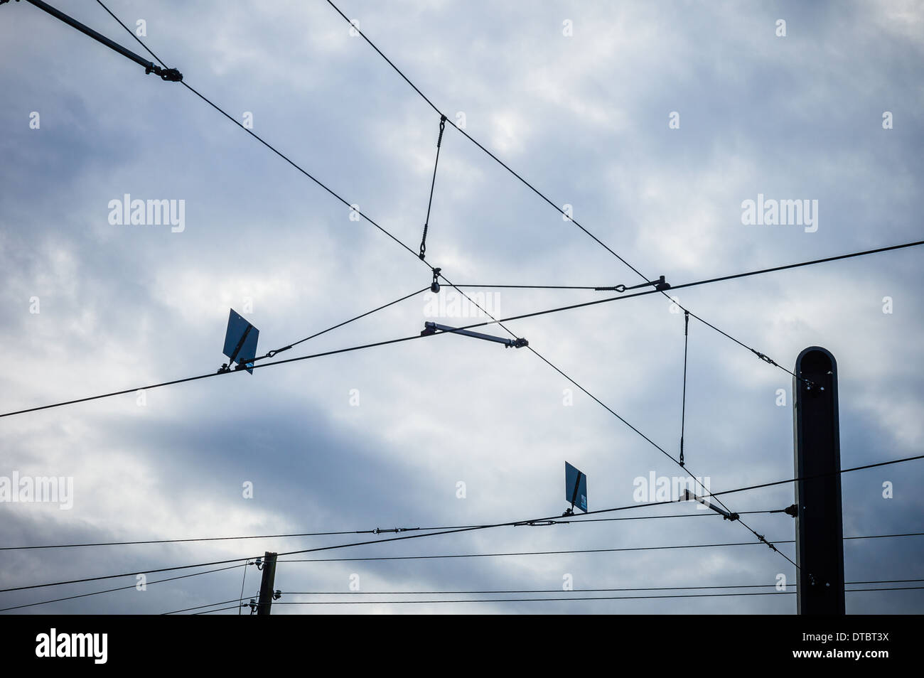 Overhead lines of a tram in front of clouded sky Stock Photo