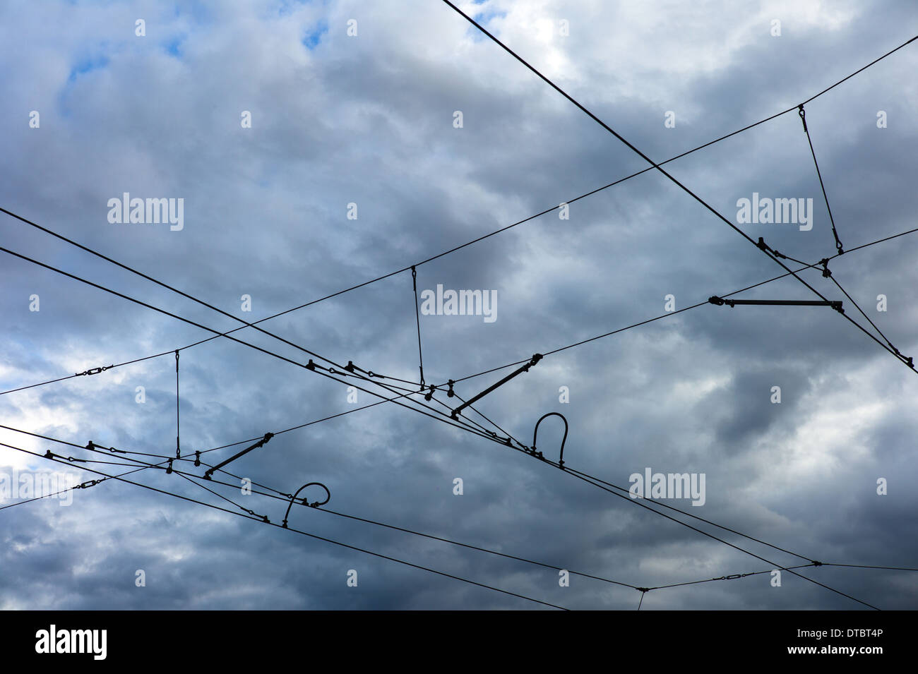 Overhead lines of a tram in front of clouded sky Stock Photo