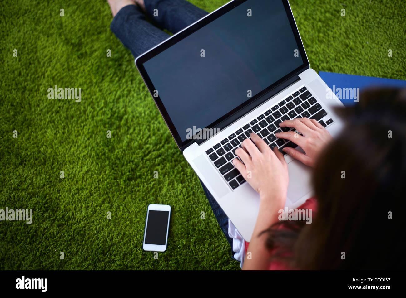 Young woman sitting on rug using laptop Stock Photo