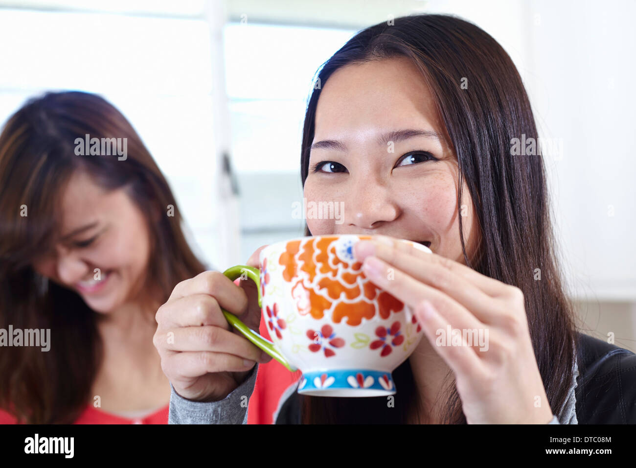Two young women in kitchen having coffee break Stock Photo