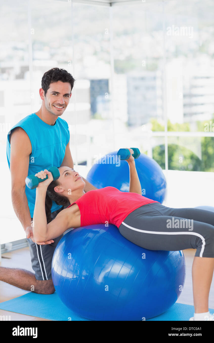 Trainer helping woman with her exercises at gym Stock Photo - Alamy