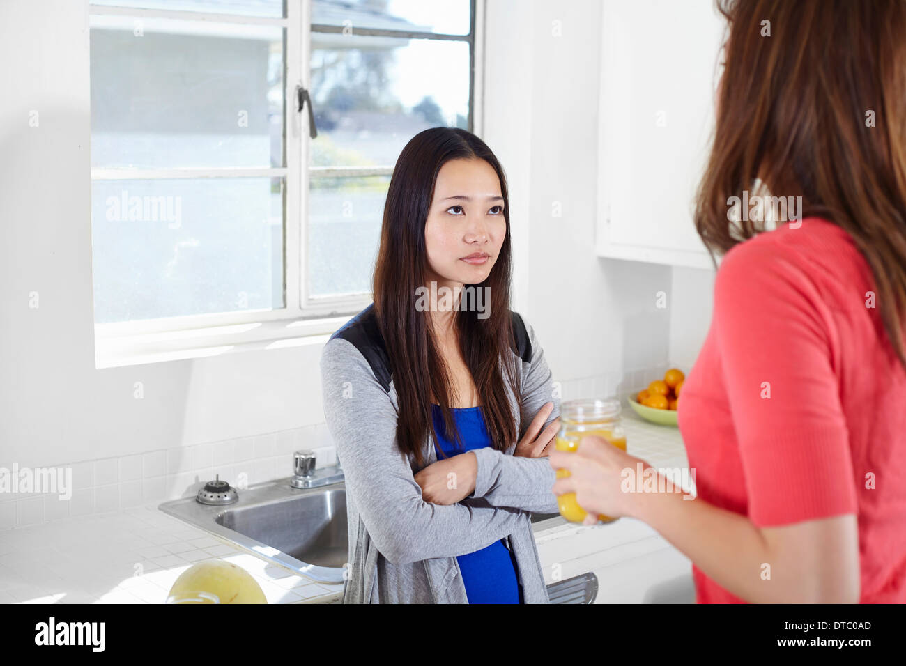 Two young women in kitchen having an argument Stock Photo