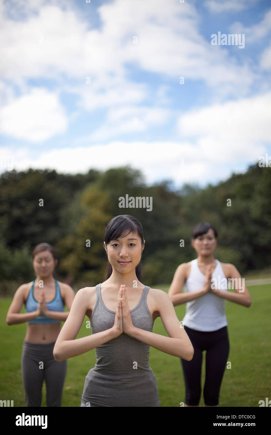 Three young women in park practicing yoga Stock Photo