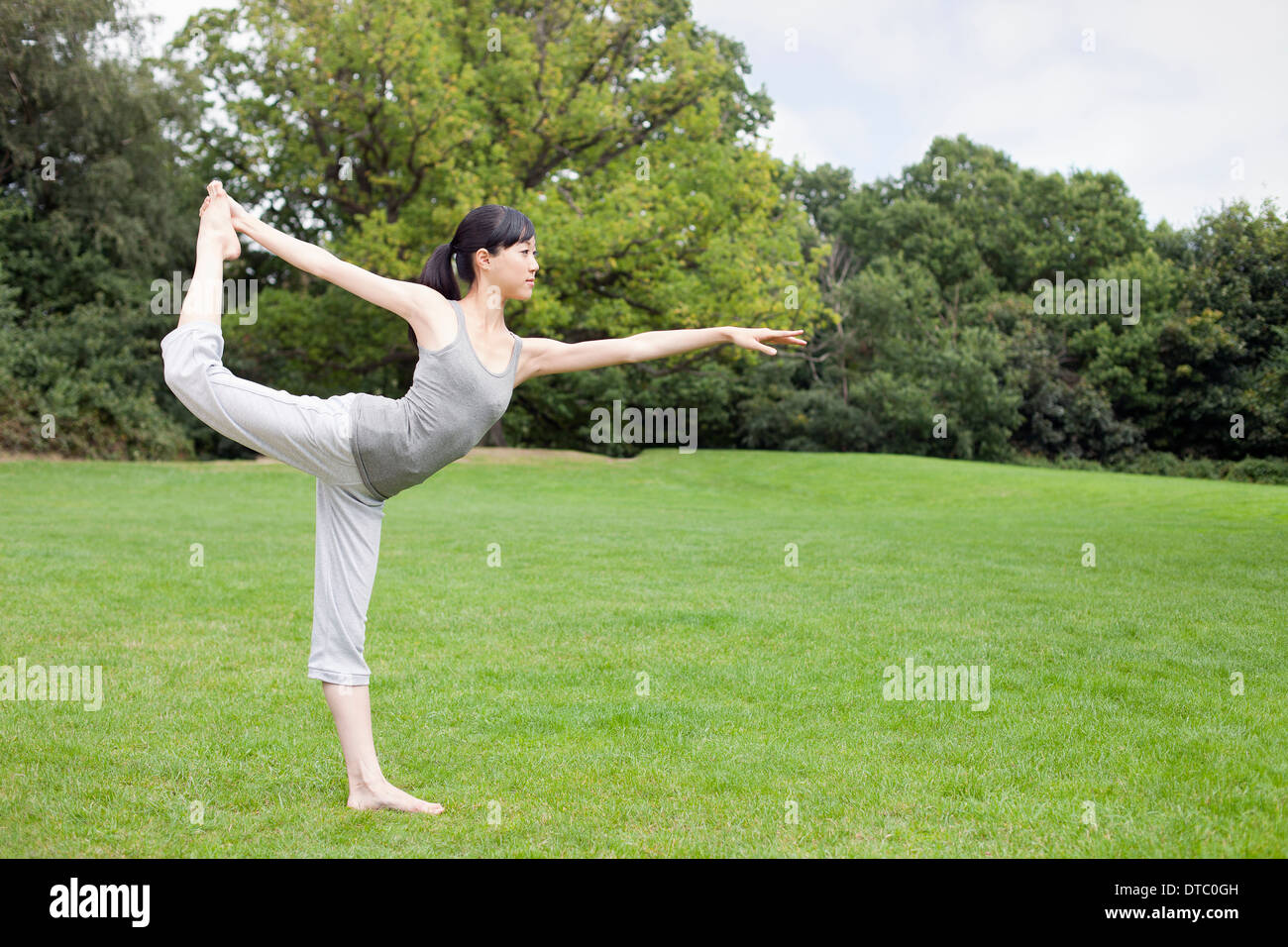 Young woman in park practicing yoga king dancer pose Stock Photo