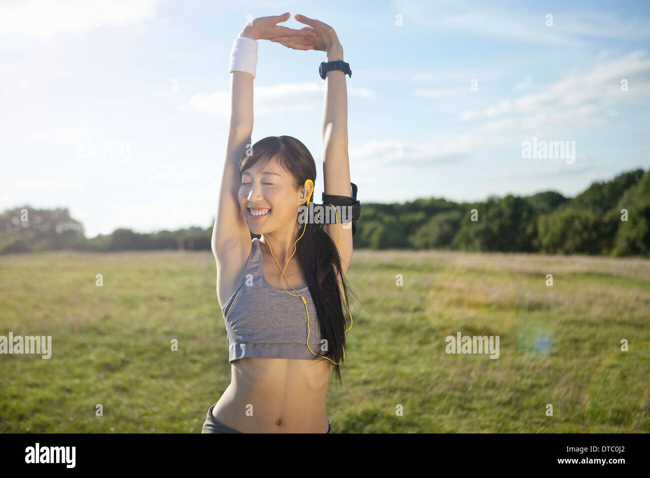 Young female runner stretching arms and warming up Stock Photo