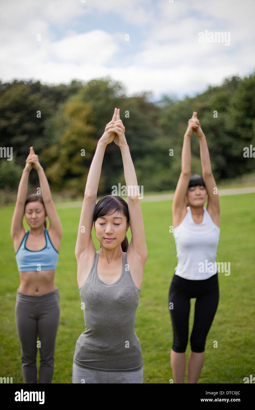 Three young women in park practicing yoga position Stock Photo