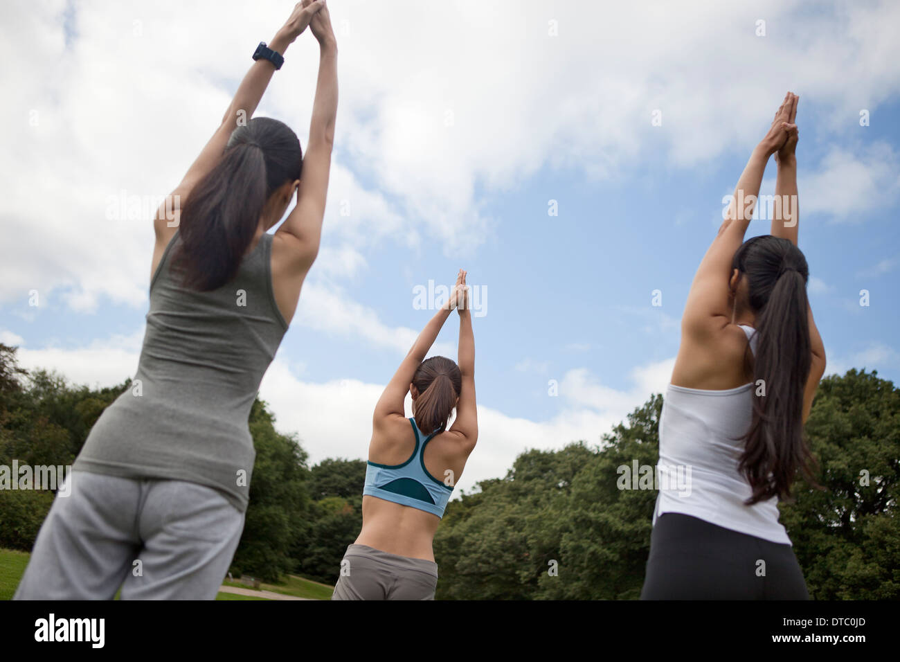 Three young women practicing yoga in park Stock Photo