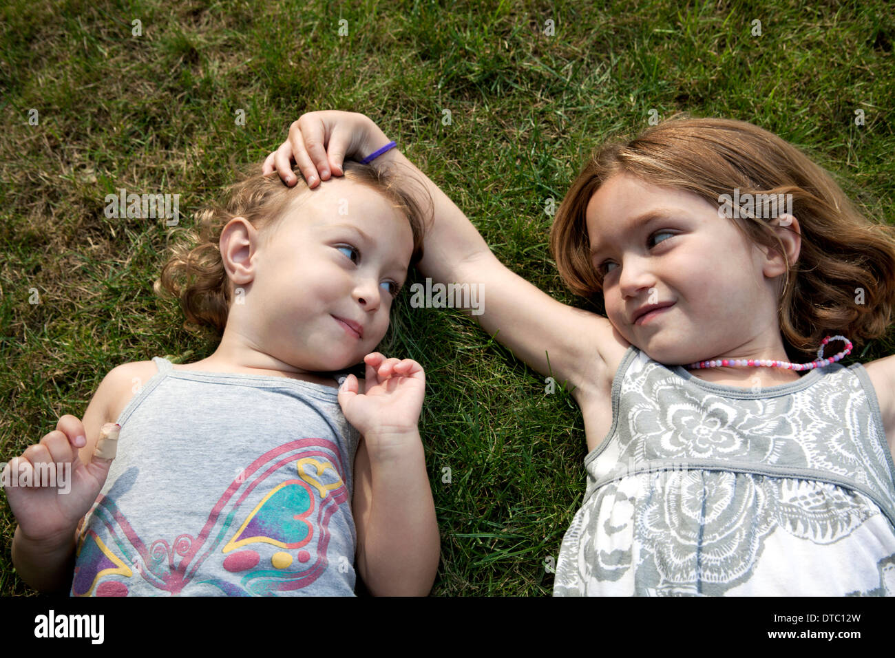 Portrait of two young sisters lying on grass Stock Photo