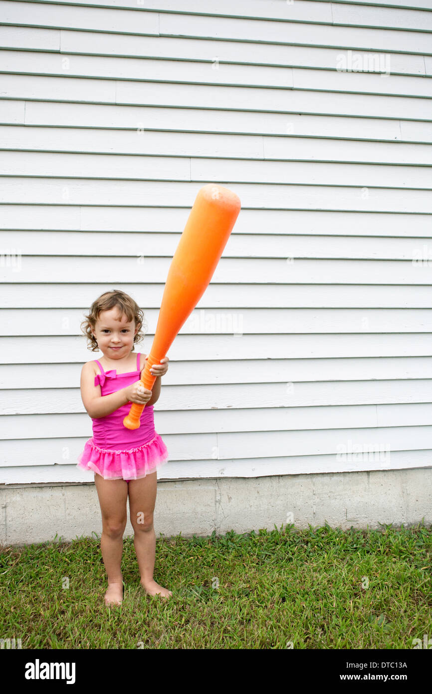 Female toddler in garden holding a large orange baseball bat Stock Photo Alamy