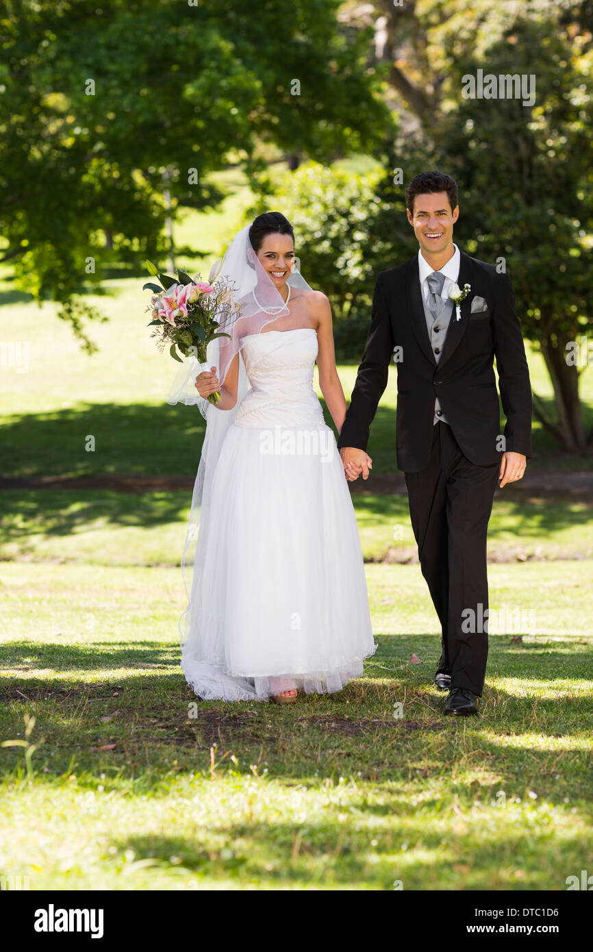 Newlywed couple holding hands and walking in park Stock Photo - Alamy