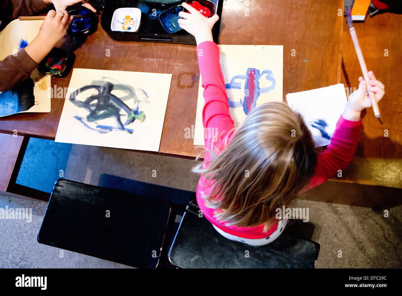 Two young siblings painting pictures at table Stock Photo