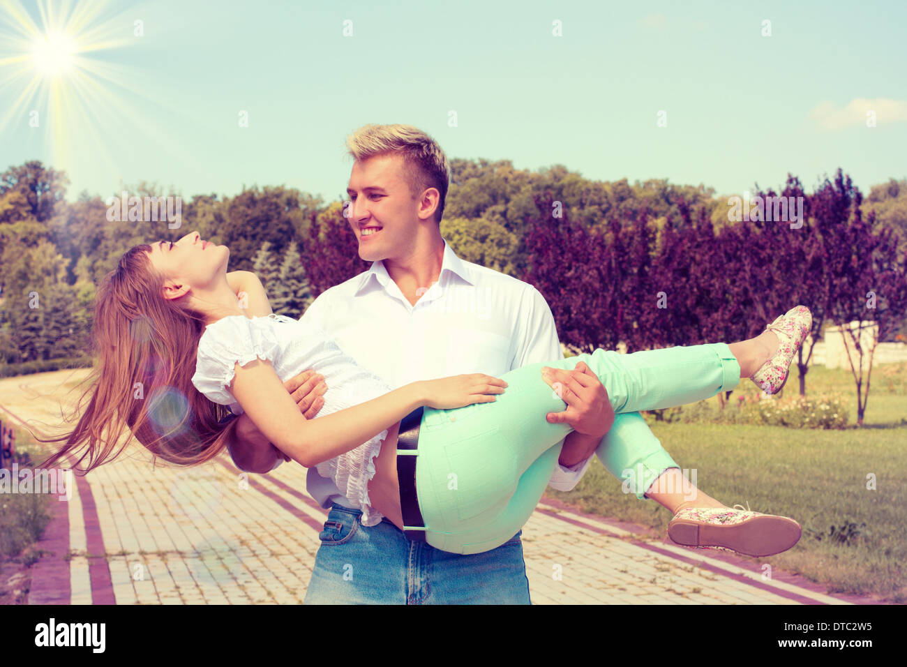 A young man is holding a young girl in her arms. Happy young couple ...