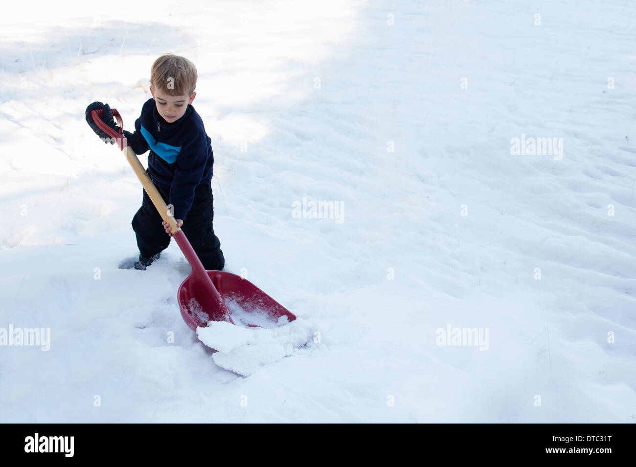 Male toddler digging snow with large shovel Stock Photo Alamy
