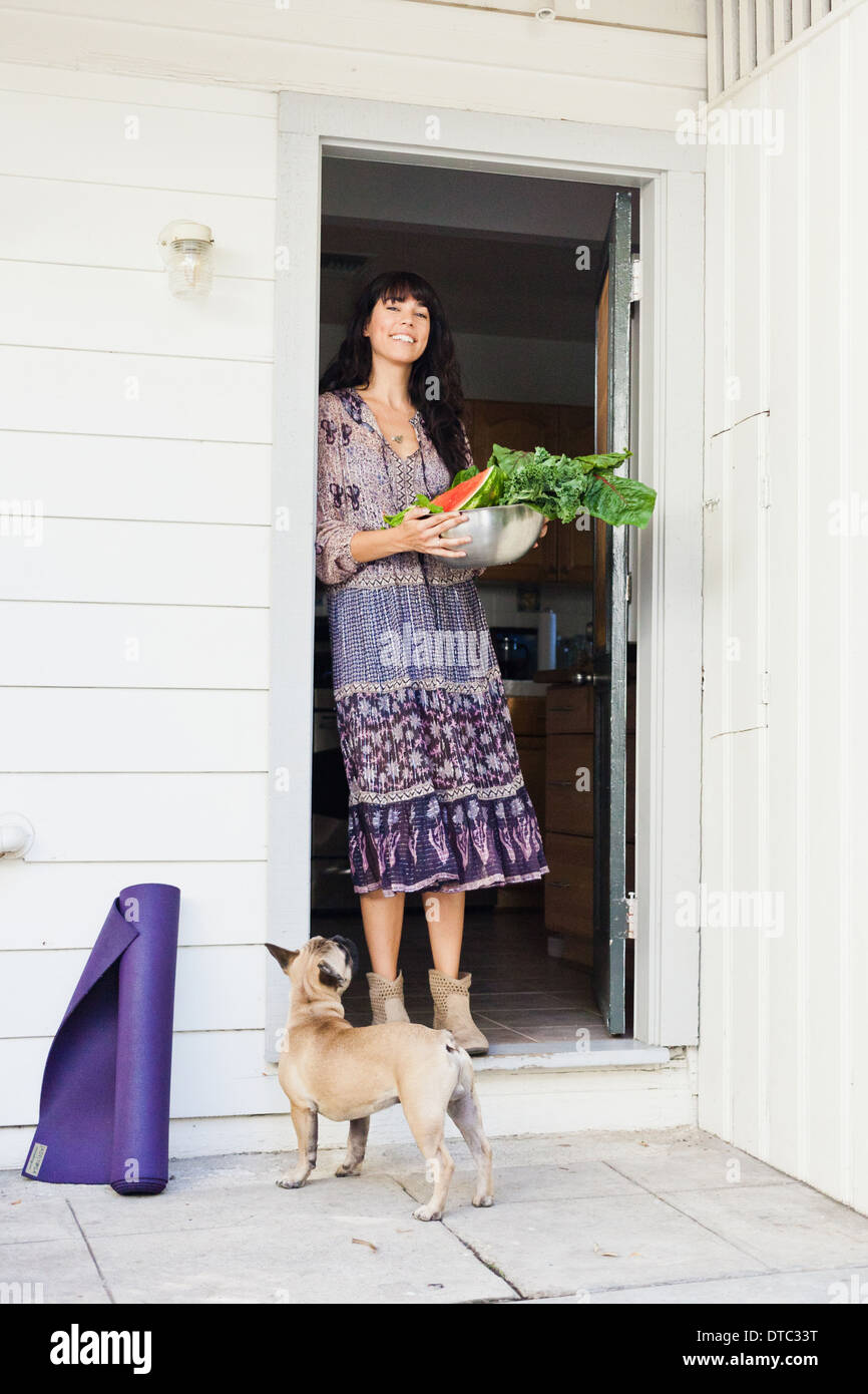 Young woman in doorway holding bowl of vegetables Stock Photo - Alamy