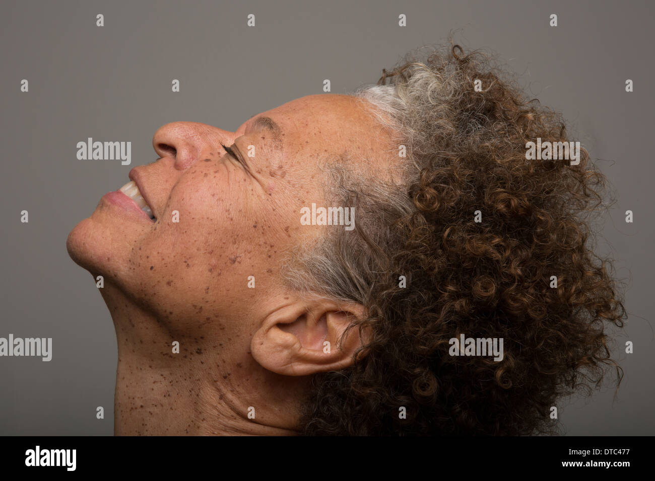 Close up studio portrait of senior woman with head back and eyes closed Stock Photo