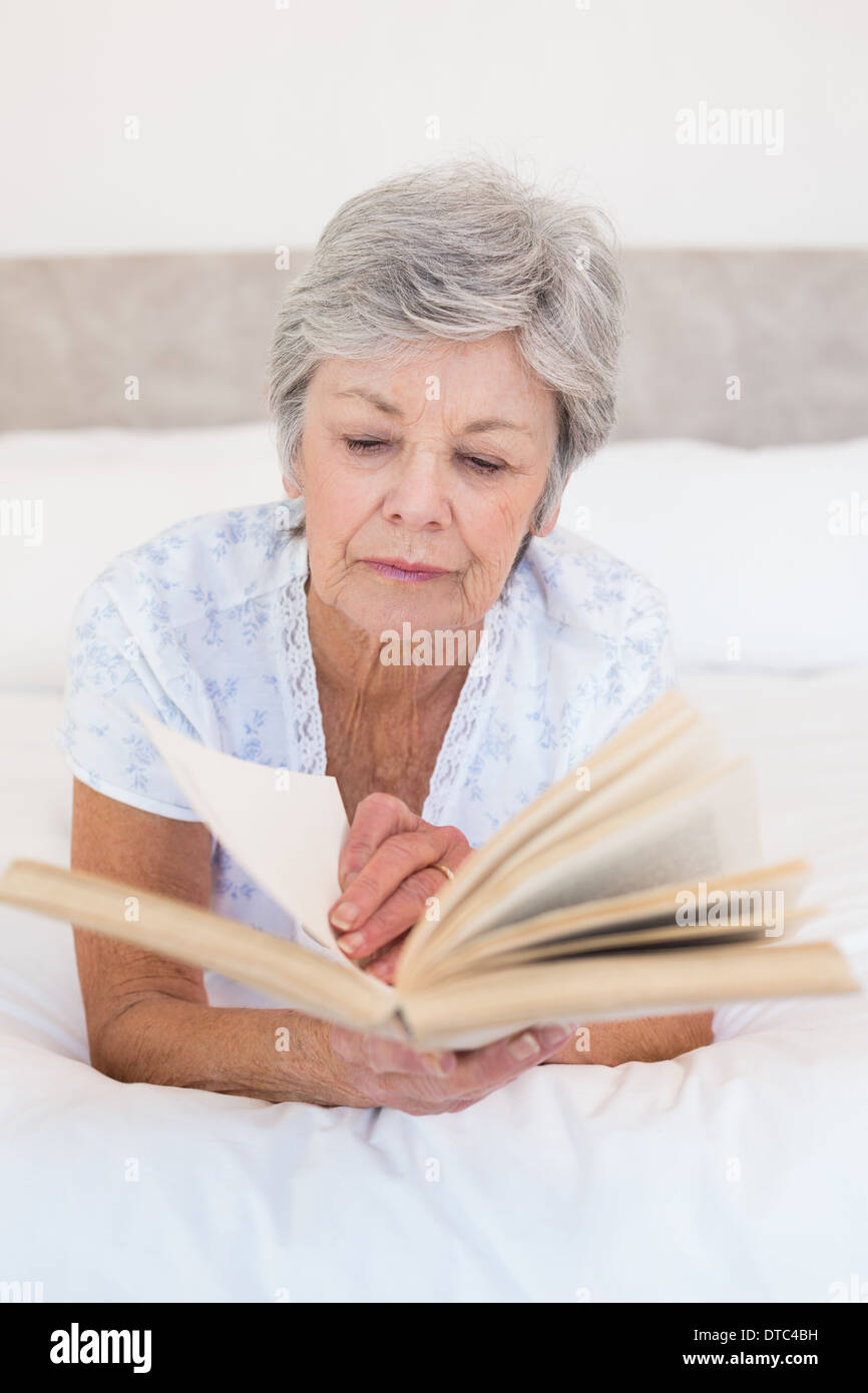 Senior woman reading story book in bed Stock Photo