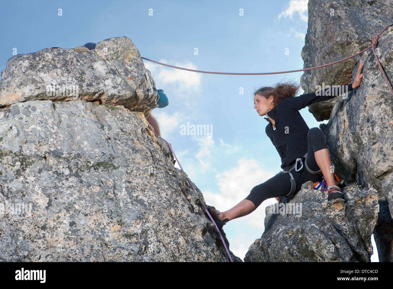 Young female rock climber sitting on rock ledge Stock Photo