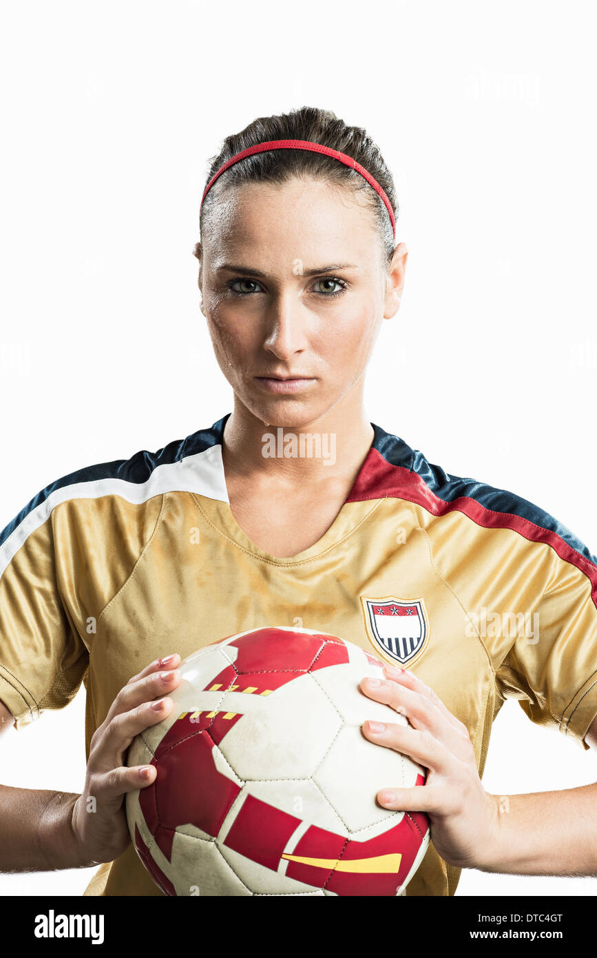Studio portrait of young female soccer player holding ball Stock Photo