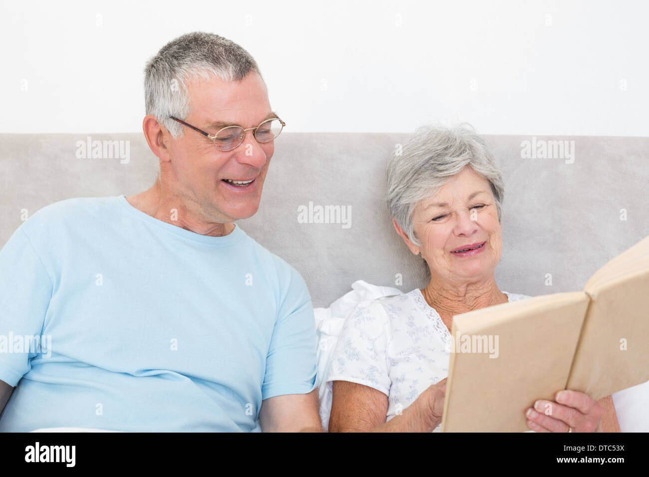 Senior couple reading book together in bed Stock Photo