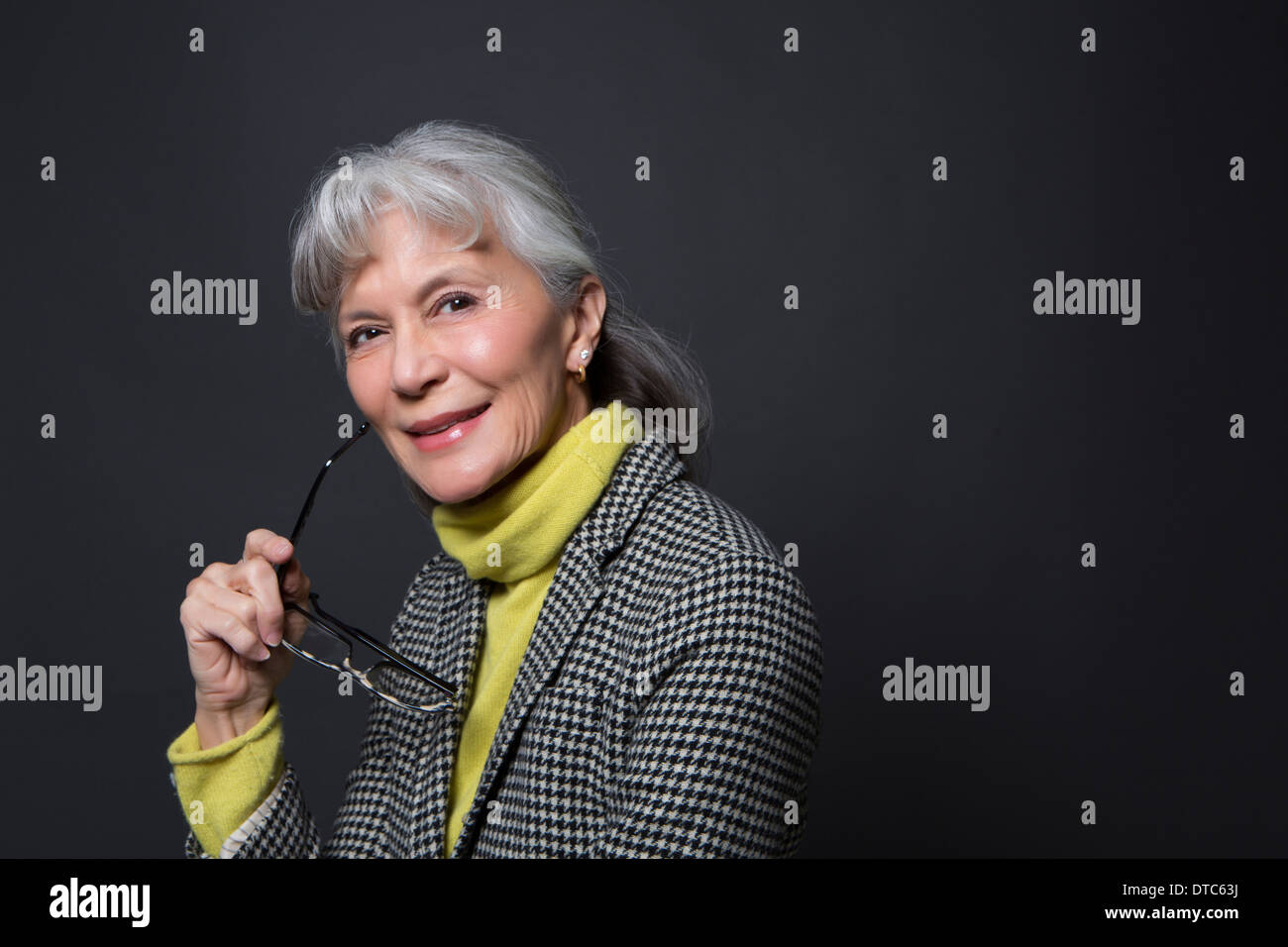 Studio portrait of wise senior woman holding spectacles Stock Photo