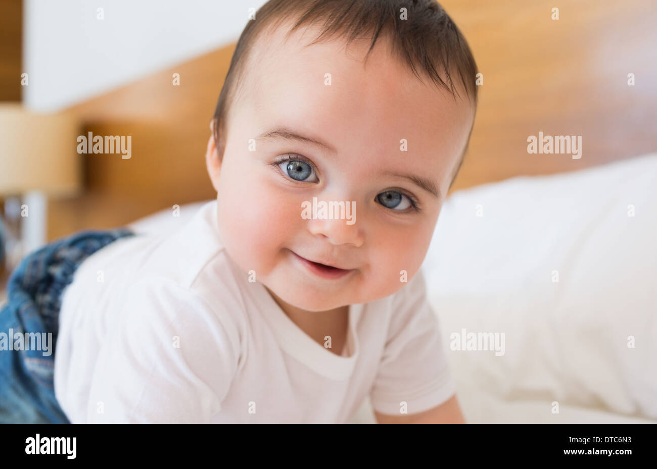 Smiling baby boy in bed Stock Photo