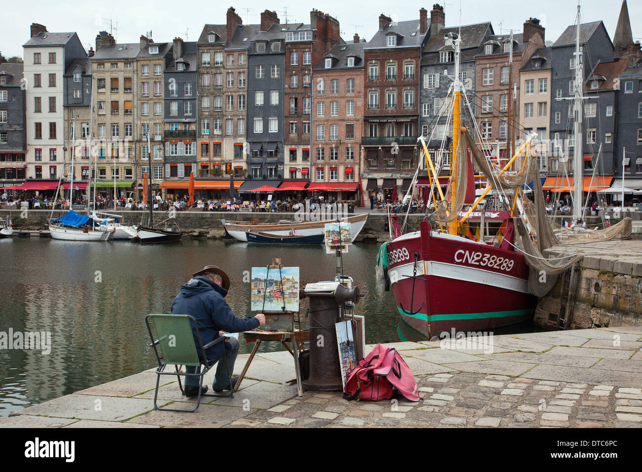 Artist painting fishing boats in the harbour at Honfleur, Normandy ...