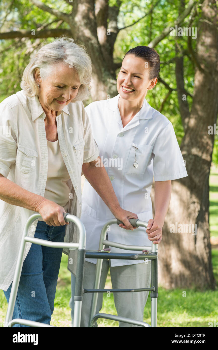 Female assisting mature woman with walker at park Stock Photo - Alamy