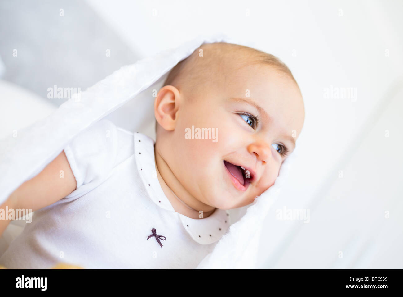 Closeup of a cheerful cute baby under comforter Stock Photo