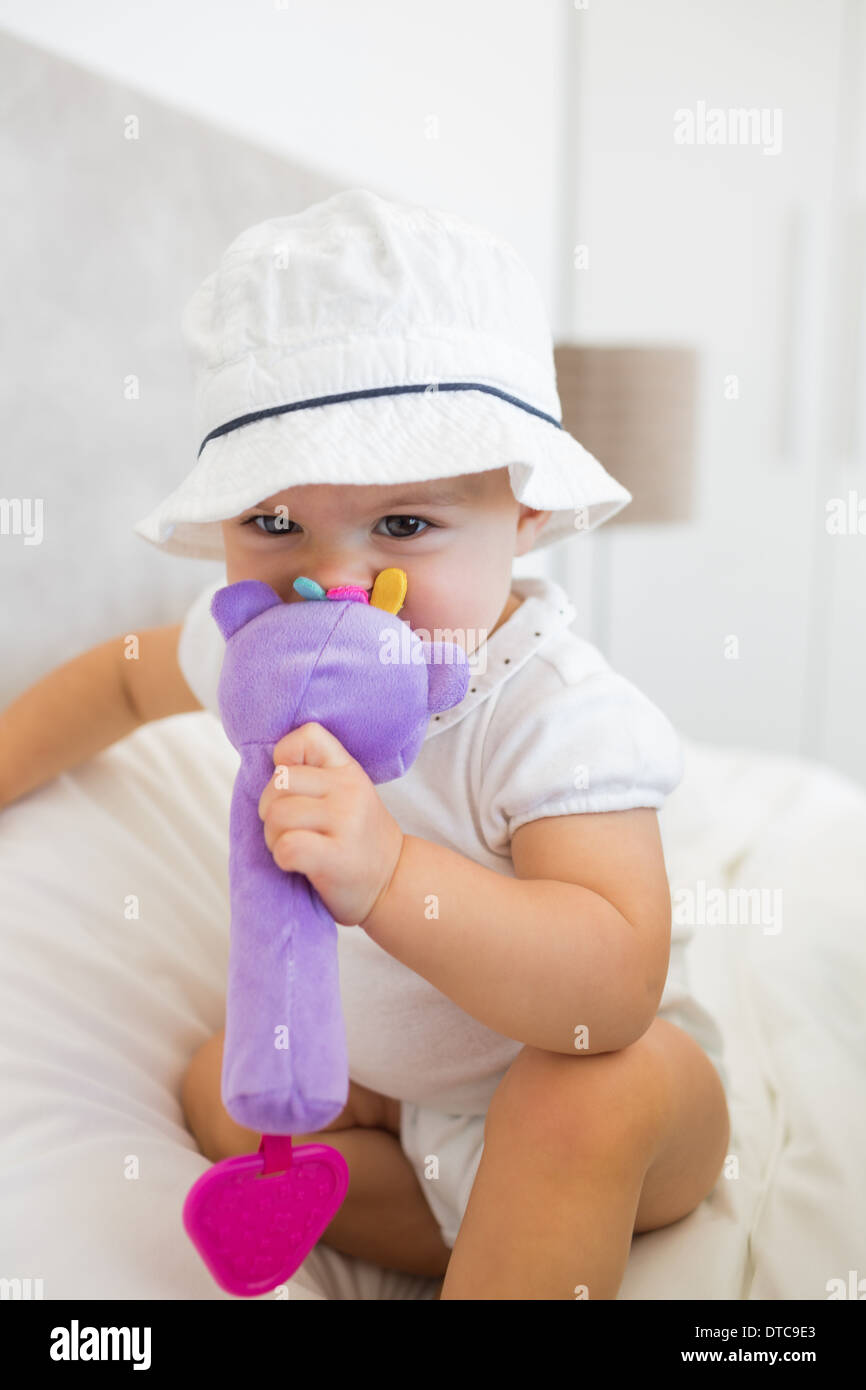 Portrait of a cute baby with toy sitting on bed Stock Photo