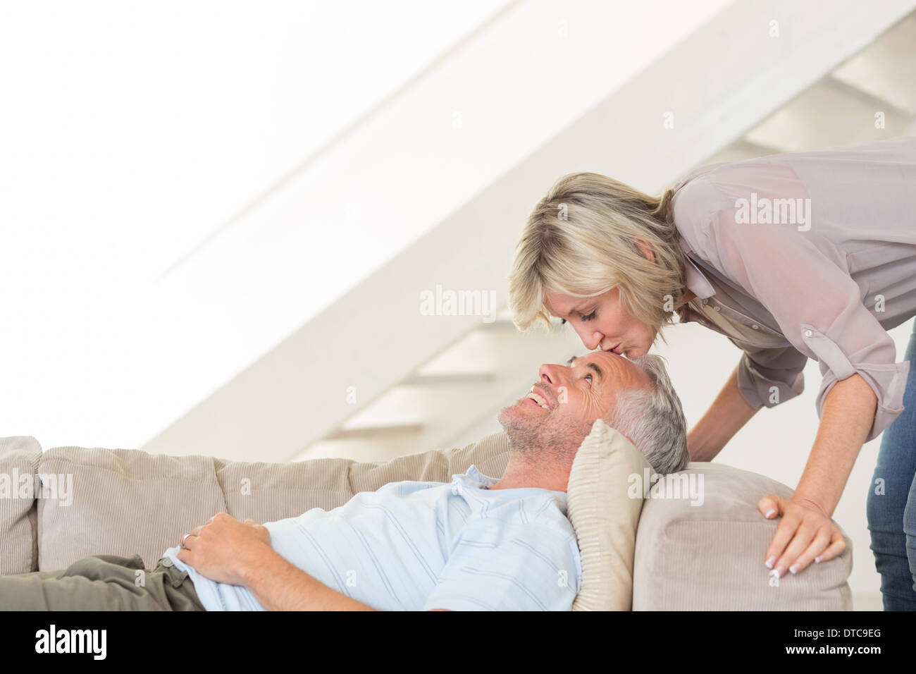 Woman kissing a mans forehead in the living room Stock Photo