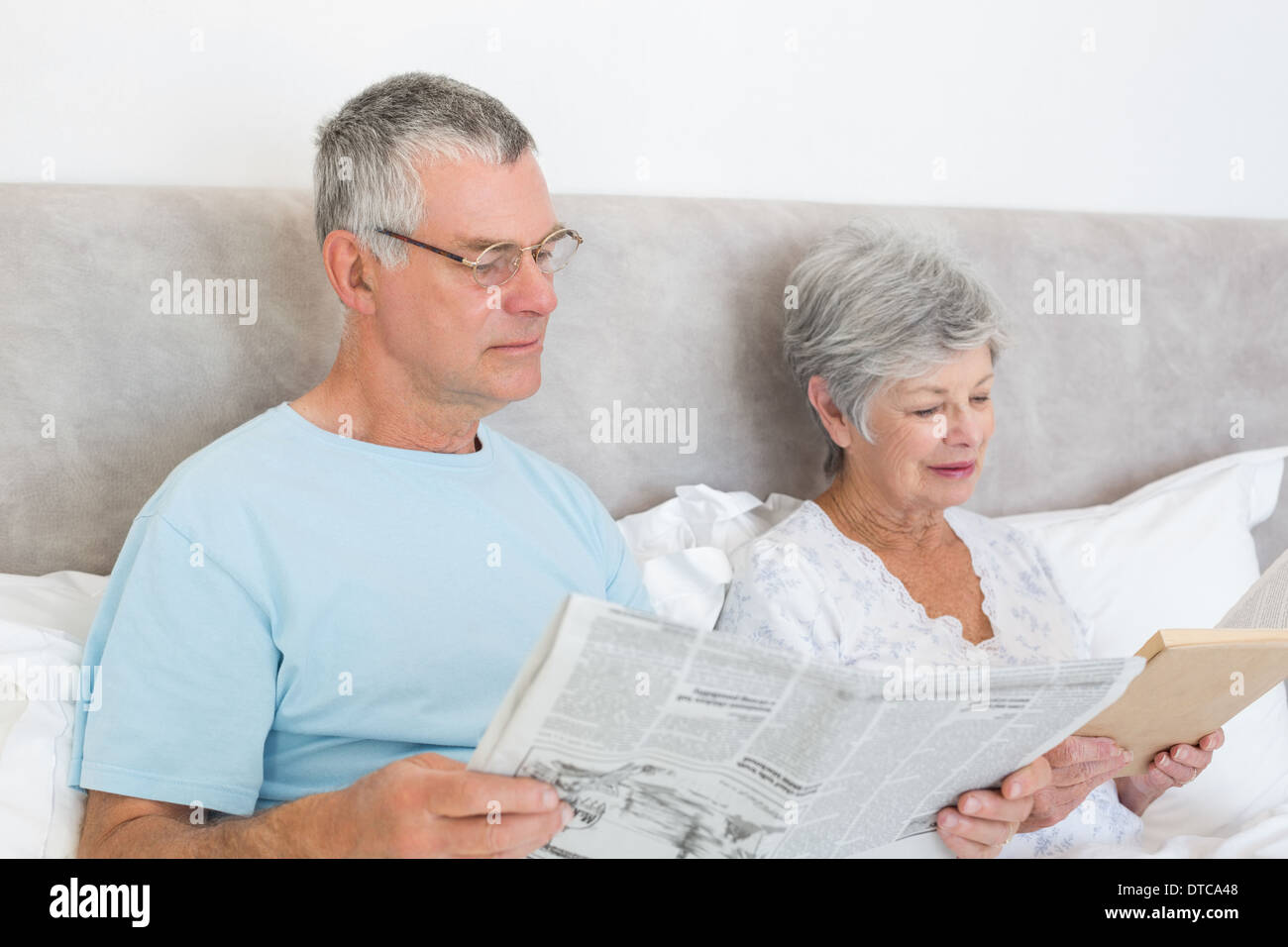 Senior couple with newspaper and book in house Stock Photo