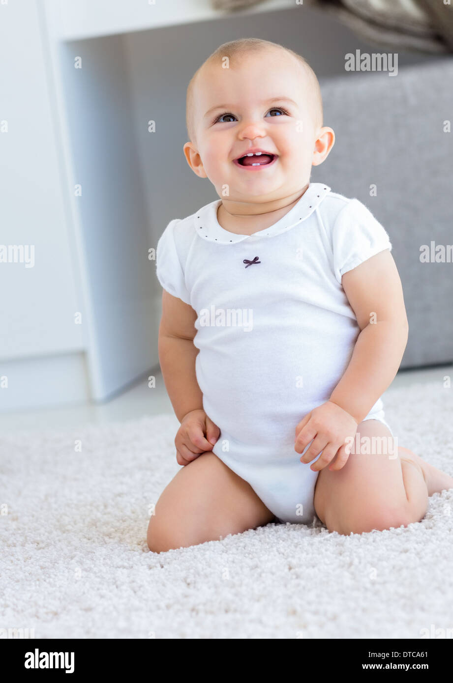 Cute cheerful baby sitting on carpet Stock Photo