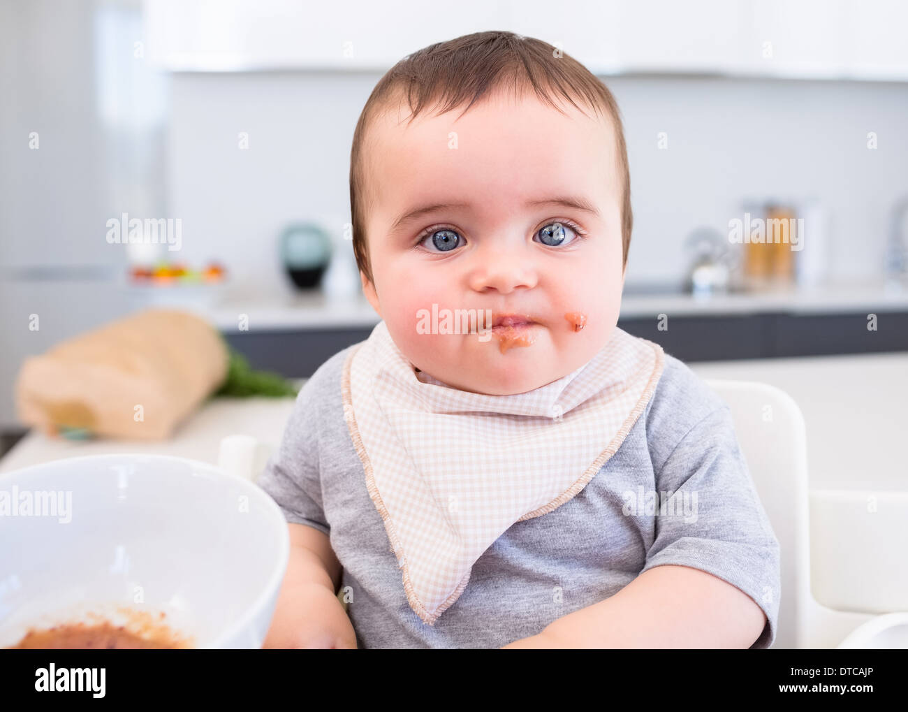 Messy baby eating food in kitchen Stock Photo