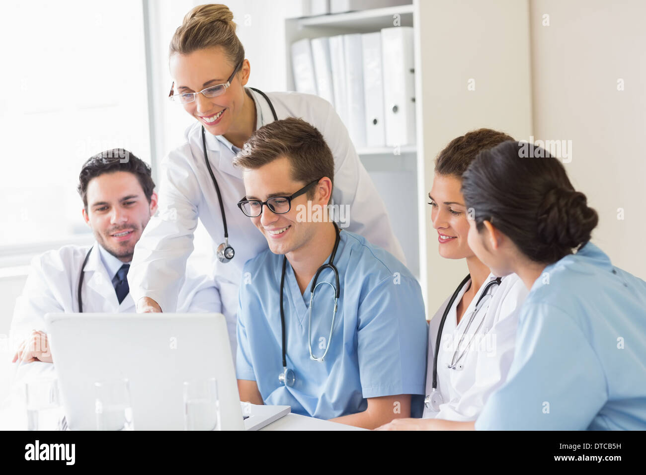 Smiling doctors and nurses discussing over laptop Stock Photo