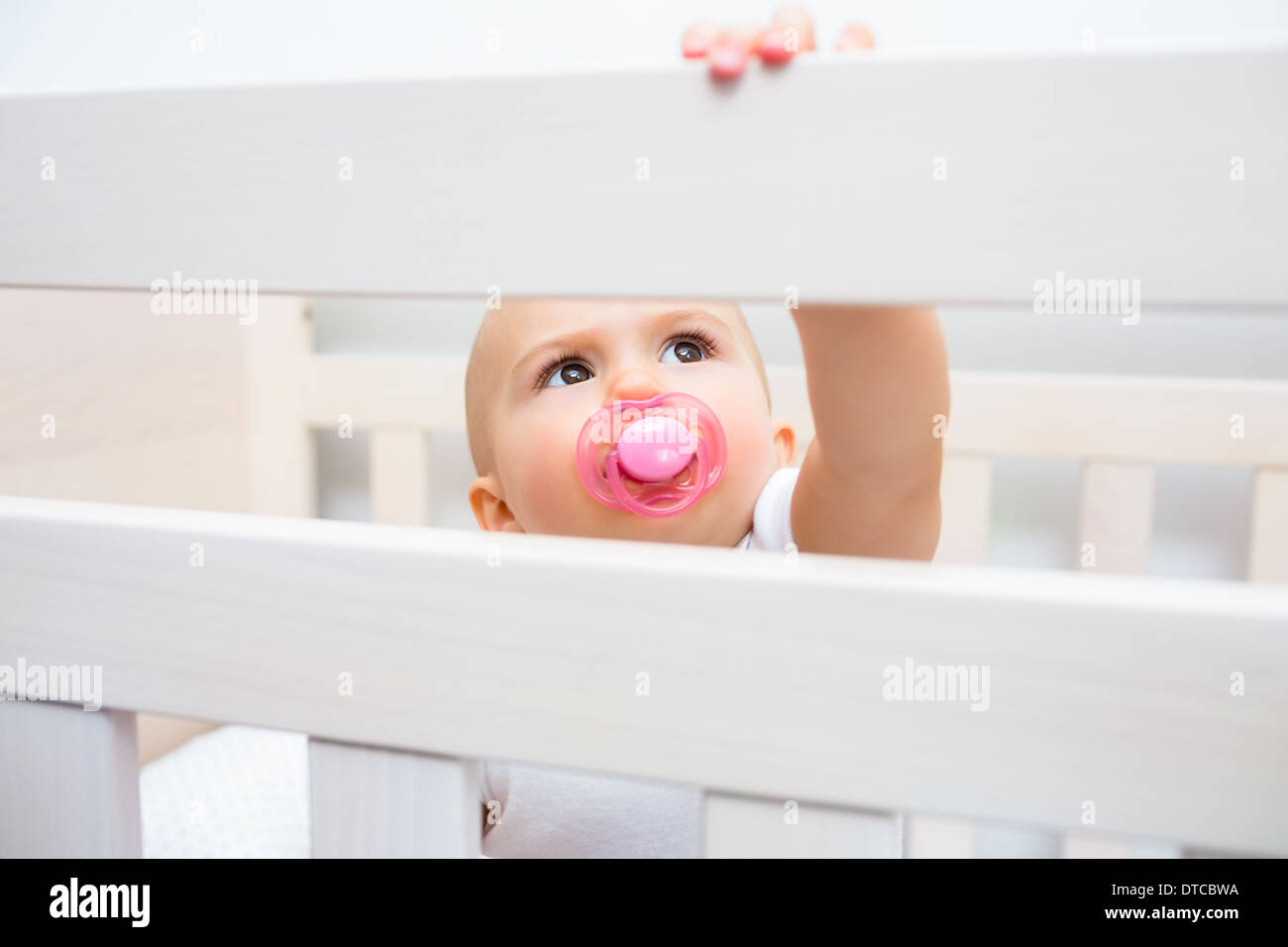 Cute baby with pacifier in mouth in the crib Stock Photo