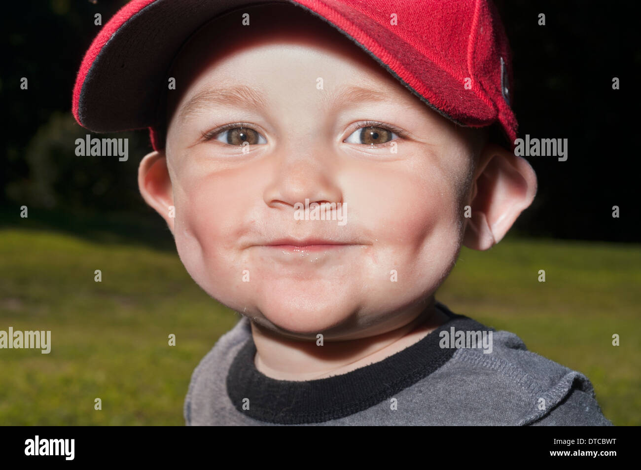 A 14-month-old Caucasian toddler wearing a red hat has his portrait taken in Prospect Park in Brooklyn, NY. Stock Photo