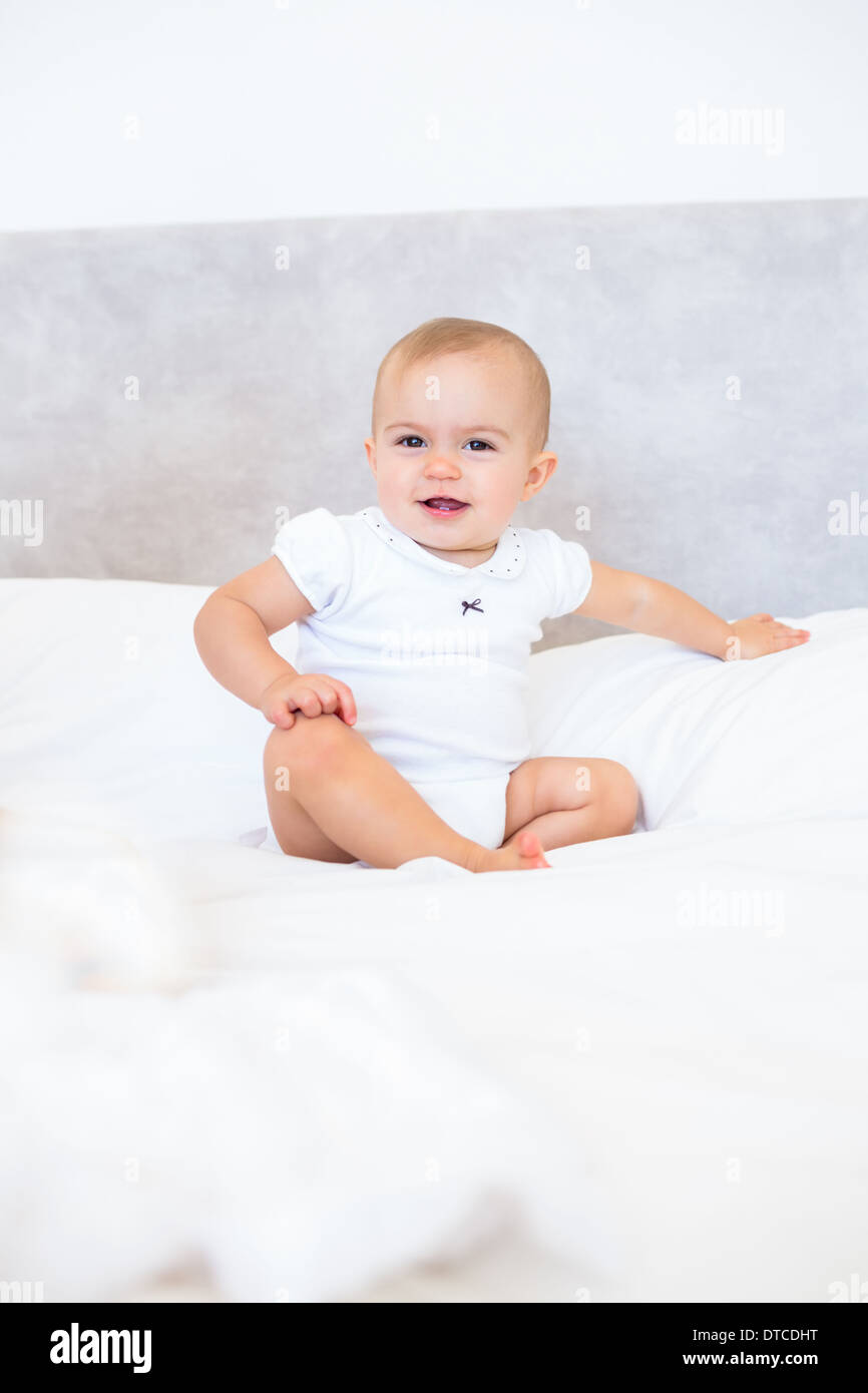 Full length portrait of cute baby sitting on bed Stock Photo