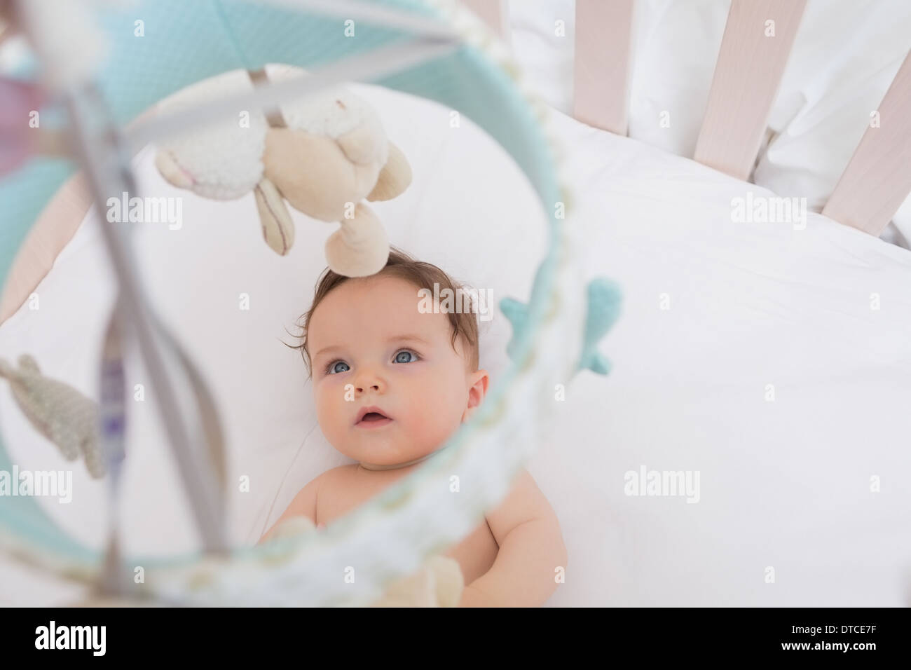 Baby looking at toys hanging in crib Stock Photo